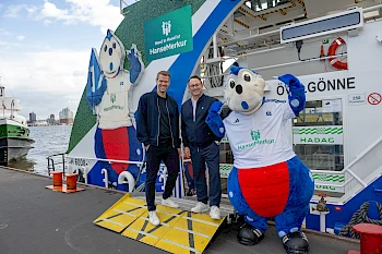 Eric Huwer, Vorstand HSV, und Eric Bussert, Vorstand Vertrieb und Marketing der HanseMerkur, bei der Einweihung der neu gestalteten Hafenfähre „Övelgönne“.